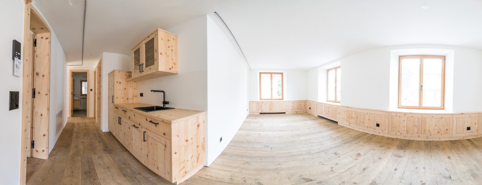 Helles, modernes Wohnzimmer mit charmanten Holzdeckenleisten und großen Fenstern, perfekt für eine gemütliche Atmosphäre und optimalen Lichteinfall.