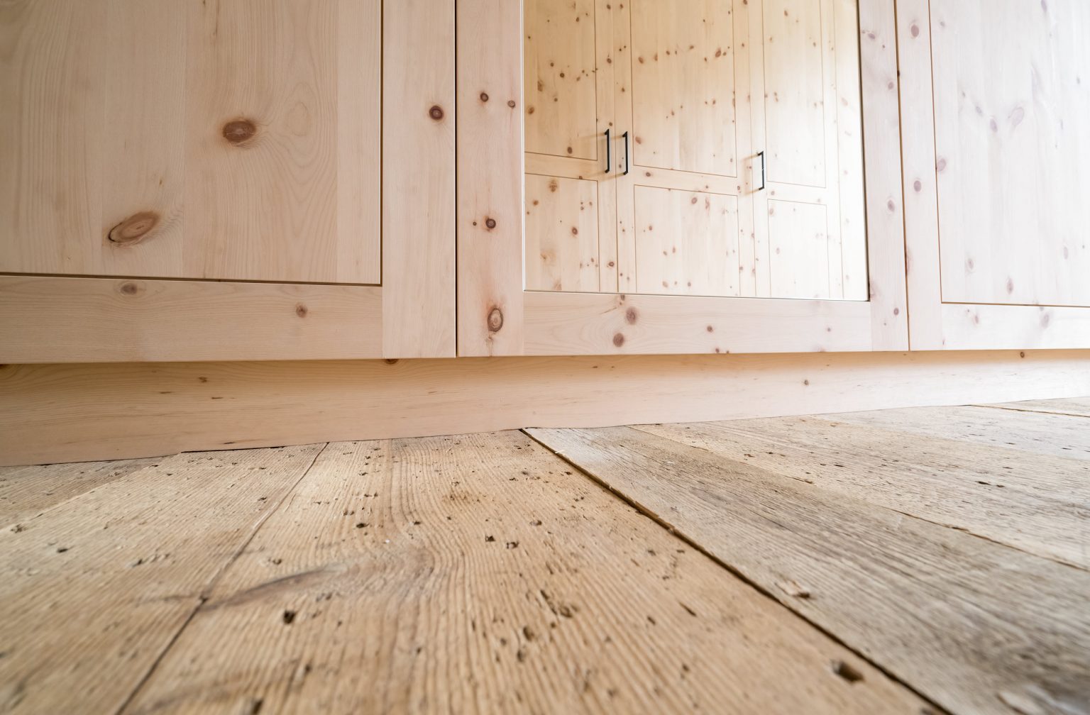 Natürliche Holzverkleidung und Holzdielenboden, hochwertiges Interior Design, nachhaltige Bauweise, gemütliches Zuhause, natürliche Materialien, Holzstruktur, robuste Holztür, Inneneinrichtung, hochwertiger Holzfußboden, rustikaler Charme.