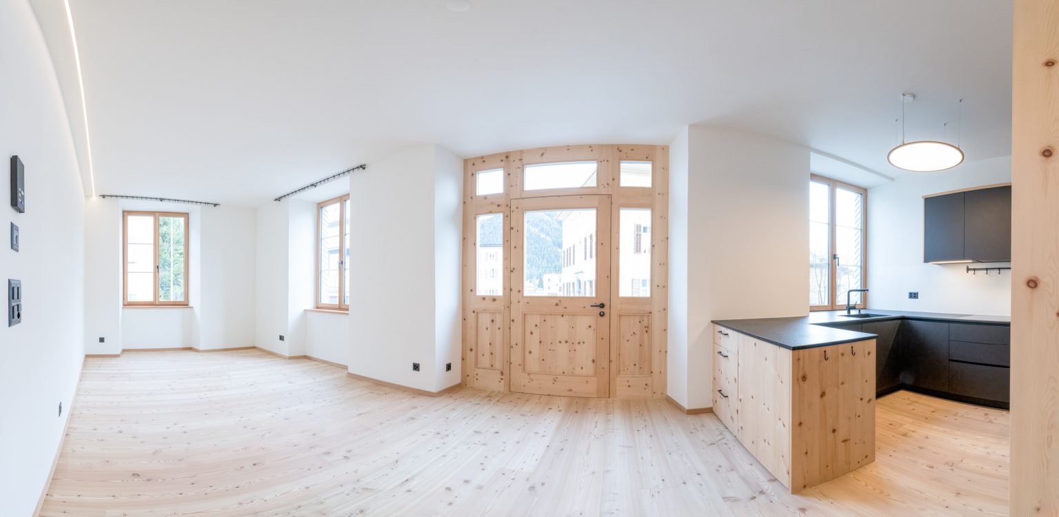 Lichter, moderne Wohnküche mit natürlichen Holzelementen und großen Fenstern, optimal für ein gemütliches Zuhause.