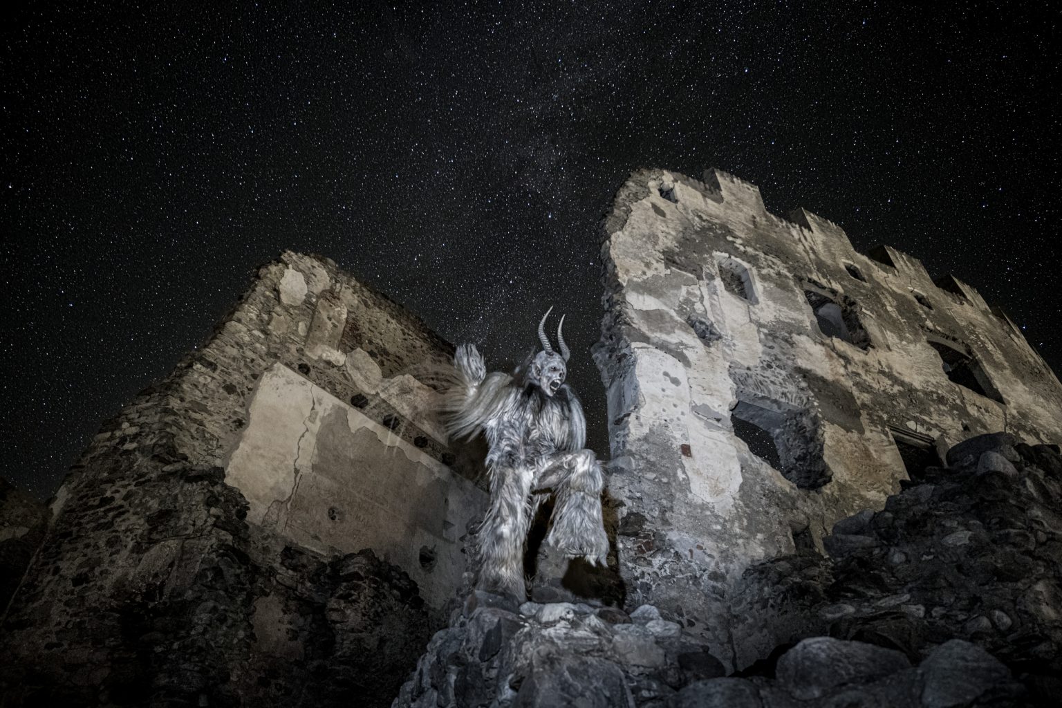 Ungewohnliche Figur in einem verfallenen Gebäude unter dem Nachthimmel mit Sternen, Kunstvolle Fotografie, starkes Mondlicht, kreative und mystische Atmosphäre, Bezug zu künstlerischer Fotografie und Visual Art.