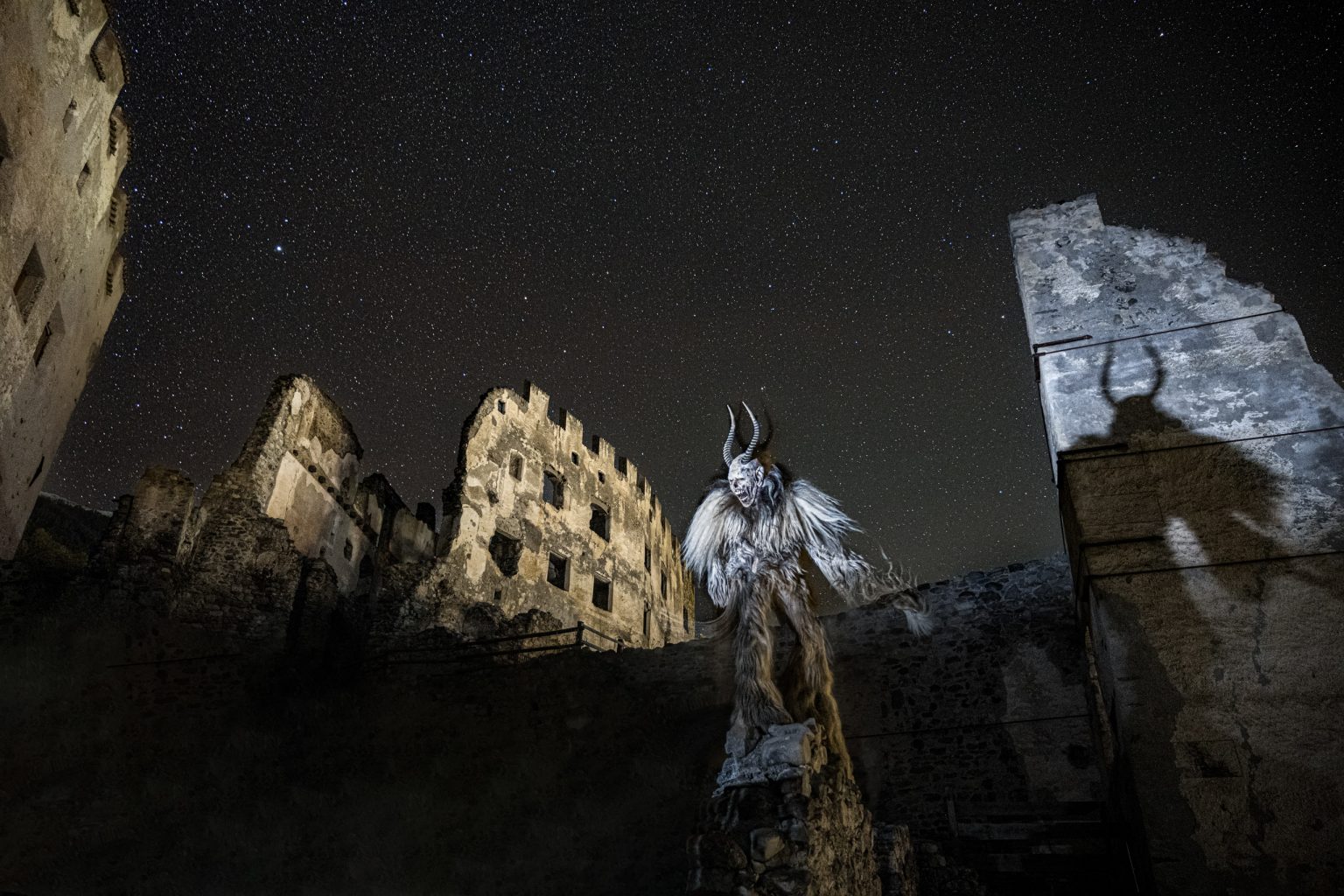 Menschlicher Szenerie-Fantasiewesen vor mittelalterlichen Ruinen bei nächtlichem Sternenhimmel, kreative Fantasy-Dekoration, episches Ambiente, Outdoor-Abenteuer, historische Kulisse, Künstliche Kreatur, mystische Figur.