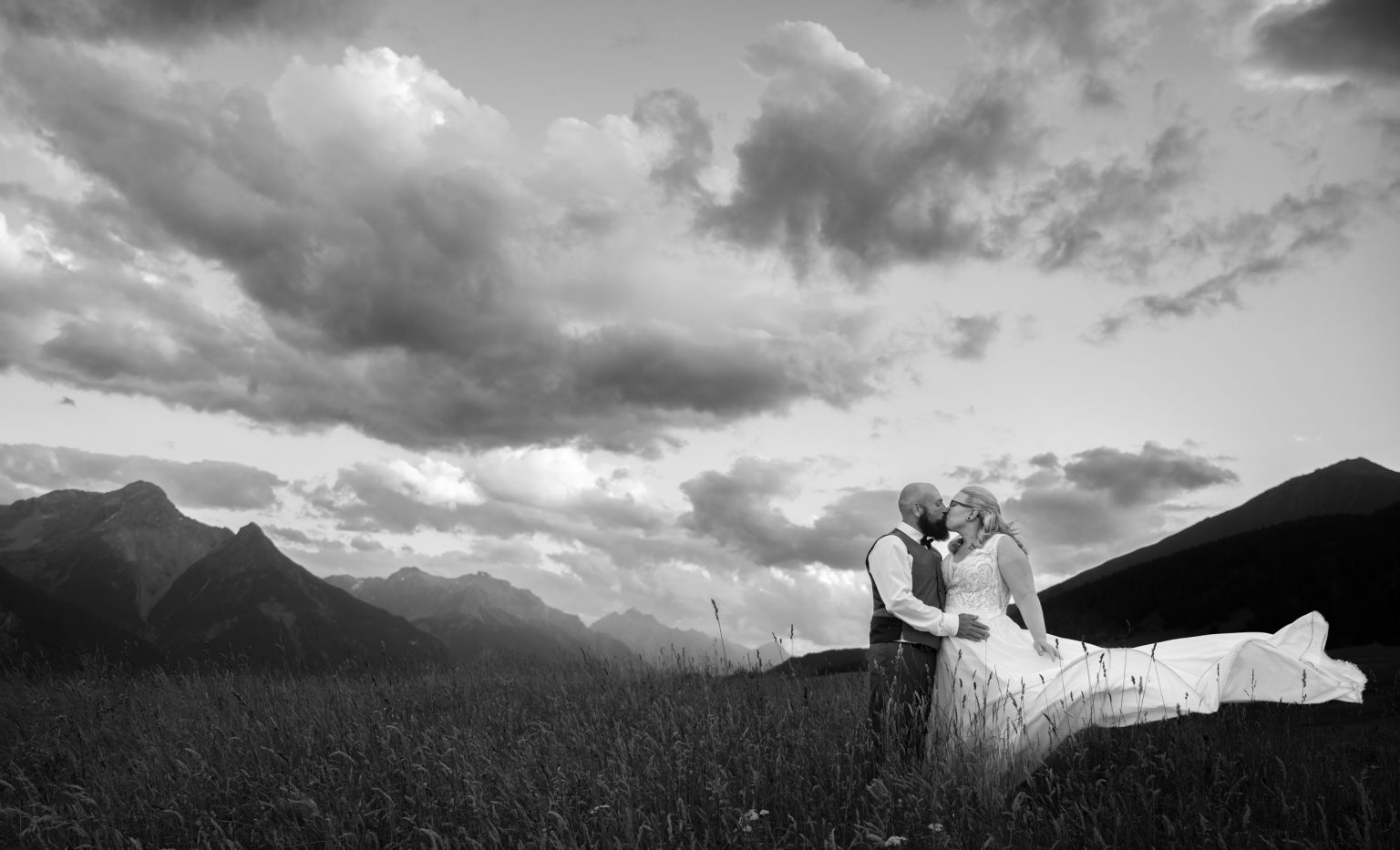 Elegantes Hochzeitsfoto von Philipp Egger im malerischen Bergland, zeigt das Brautpaar in einer liebevollen Umarmung bei Sonnenuntergang.