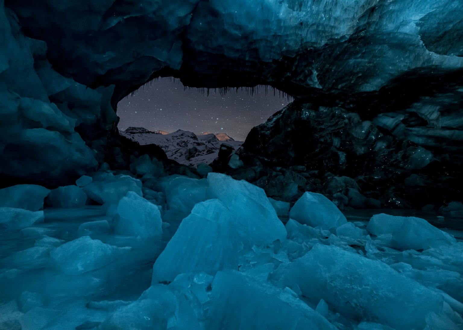 Philipp Egger, Kathedrale des schwindenden Eises: blaue Eishöhle, Blick auf verschneite Gipfel unter Sternenhimmel — International Photography Awards 2026.